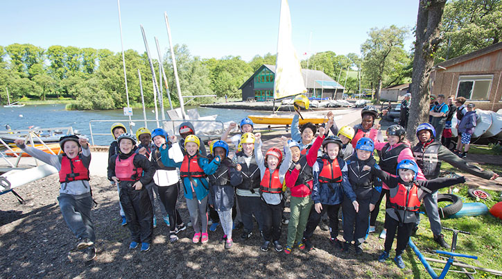 A group of children at the CCC Dinhy Section, at Bardowie Loch. The children are cheering in front of the boats.